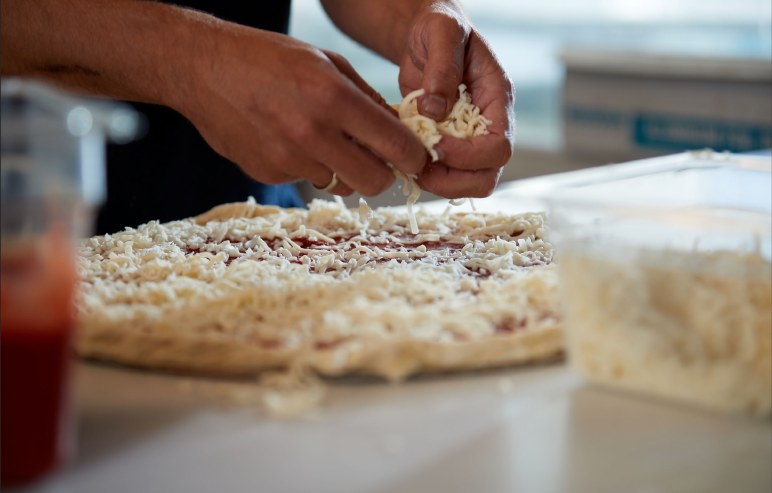 Fresh cheese being added to a pizza