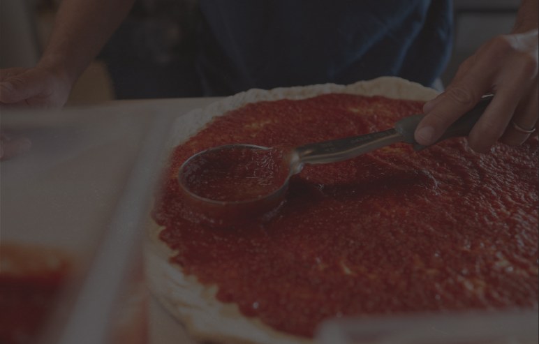 Fresh sauce being spread on pizza dough